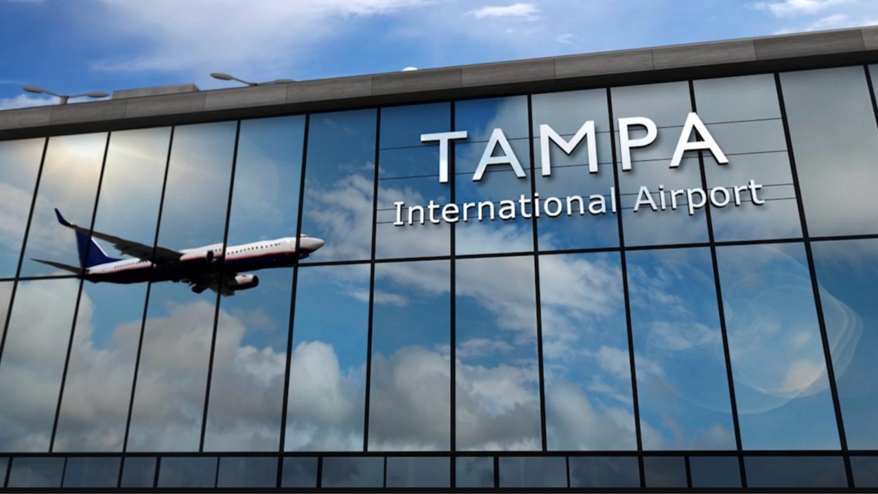 Exterior view of Tampa International Airport with an airplane flying past the glass facade.