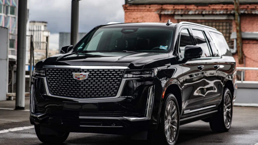 A black Cadillac SUV parked in an urban setting, featuring a luxurious design and prominent grille.